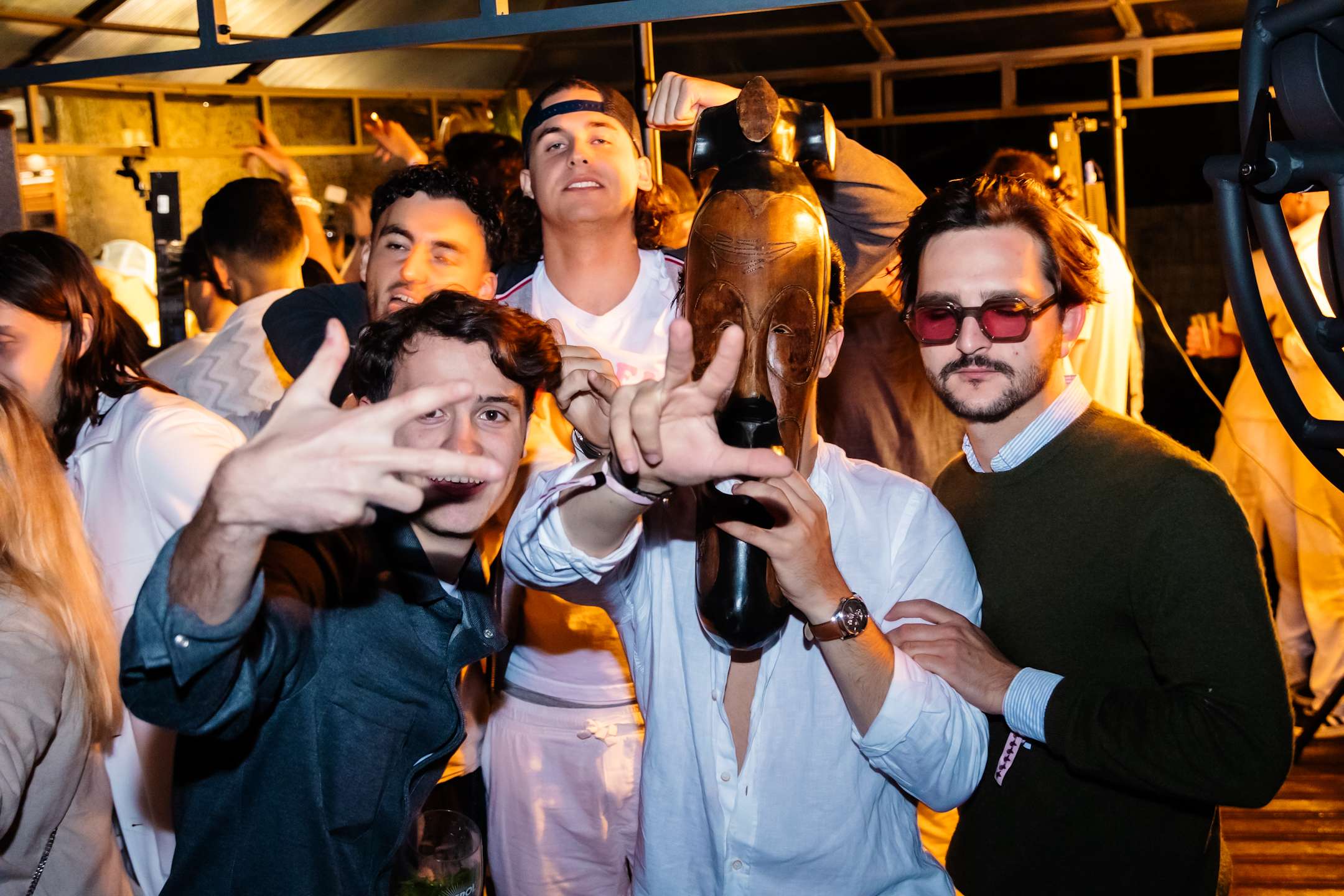 Un groupe d’amis pose face caméra dans une ambiance festive et décontractée au cœur de la soirée.