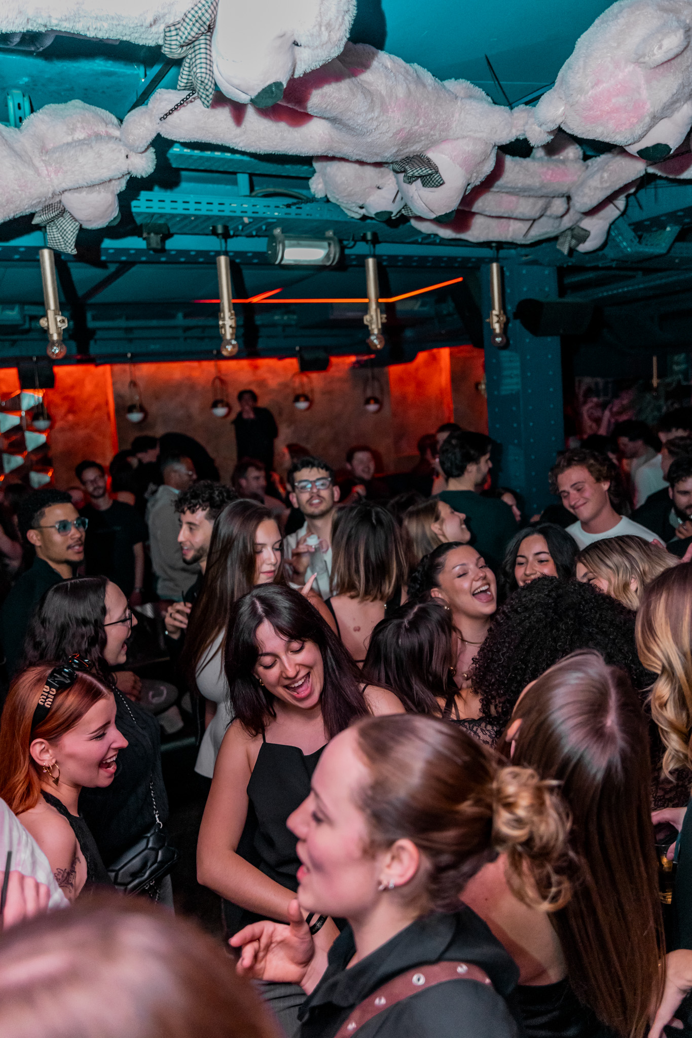 Une foule compacte profite d’une ambiance festive sous les ours suspendus et les lumières roses du club.