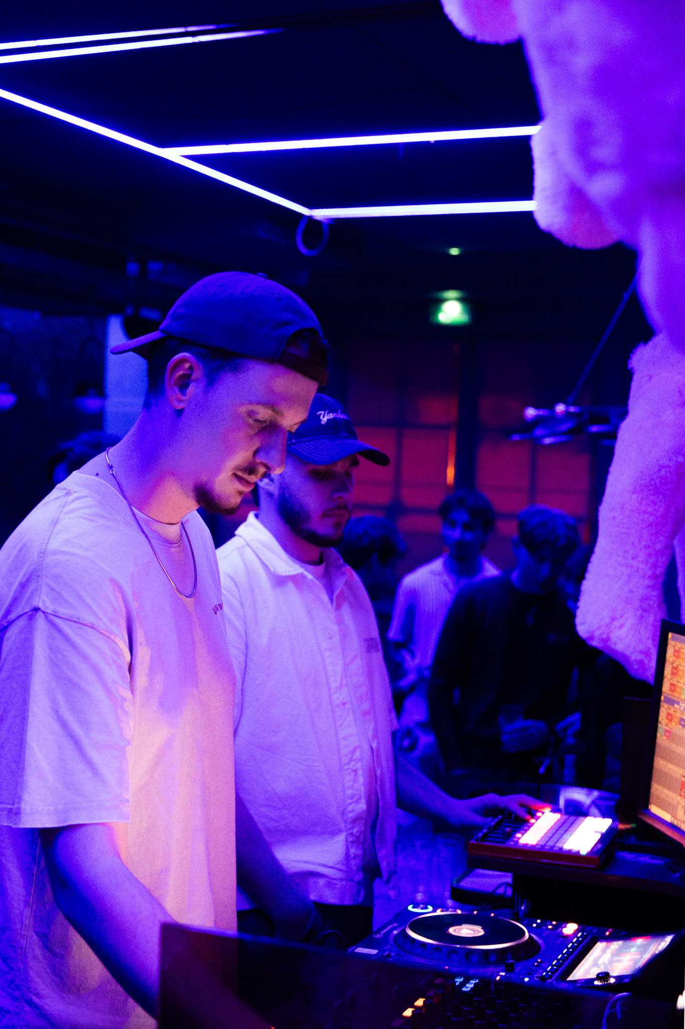 Duo de DJs en pleine performance dans une ambiance club futuriste.