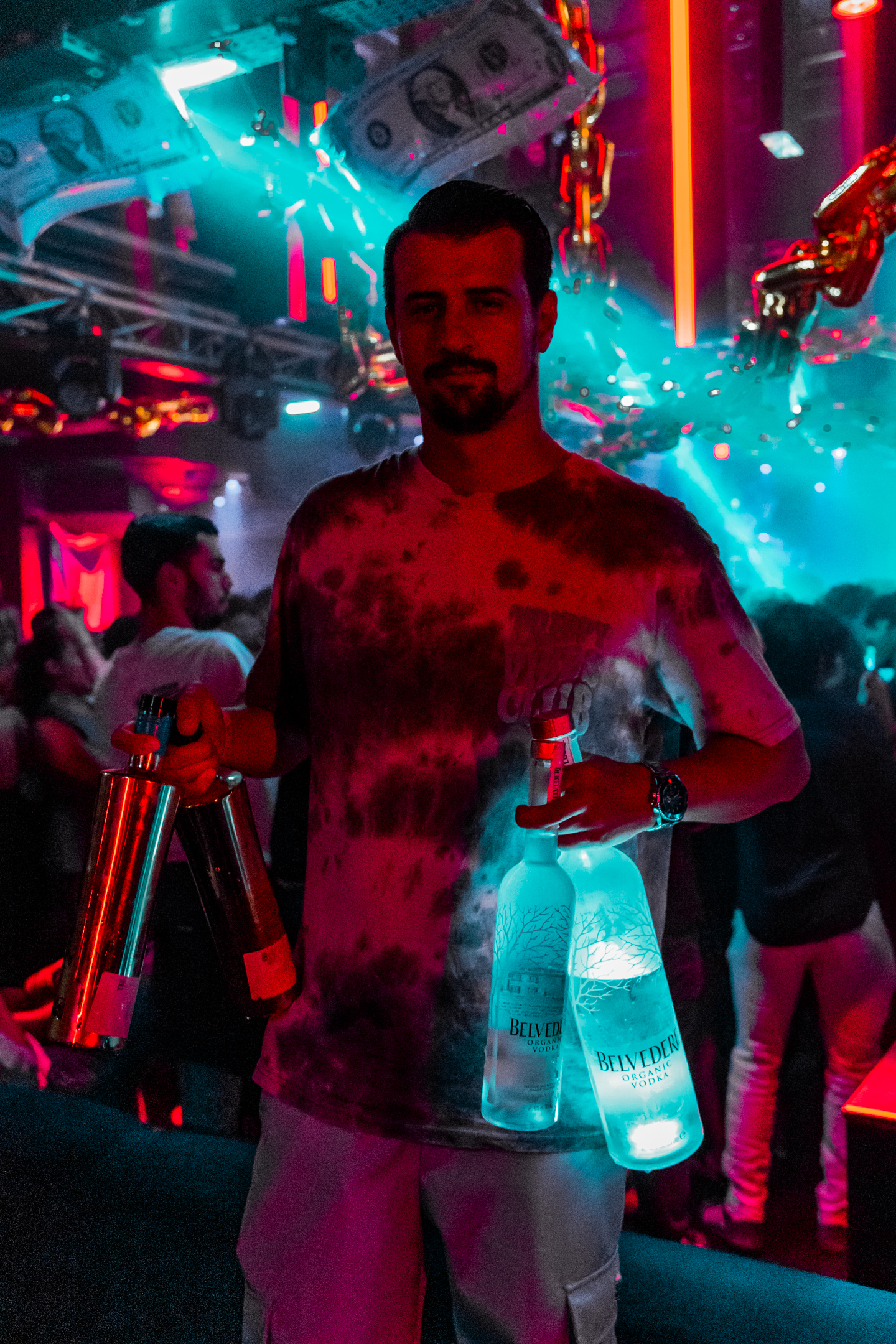 Une scène sombre et colorée montre le public réuni autour d’un performer au centre du dancefloor.